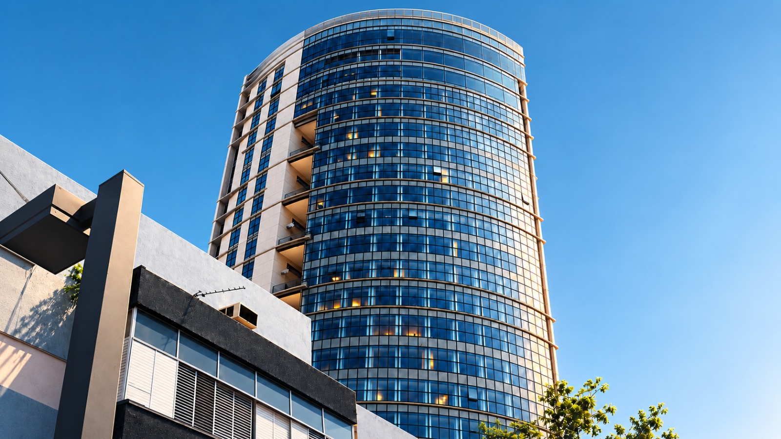 Curved glass office tower rising against a clear blue sky